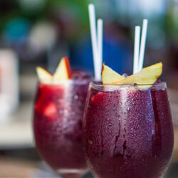 Two Beach Plum Sangria Spritzer's in stemless wine glasses with straws