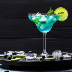 A cold Lake Time Addiction Margarita sitting on a tray with ice and lime