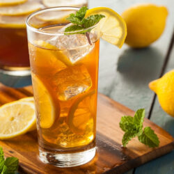 An ice cold glass of Phantom Lemon Tea garnished with mint and a slice of lemon