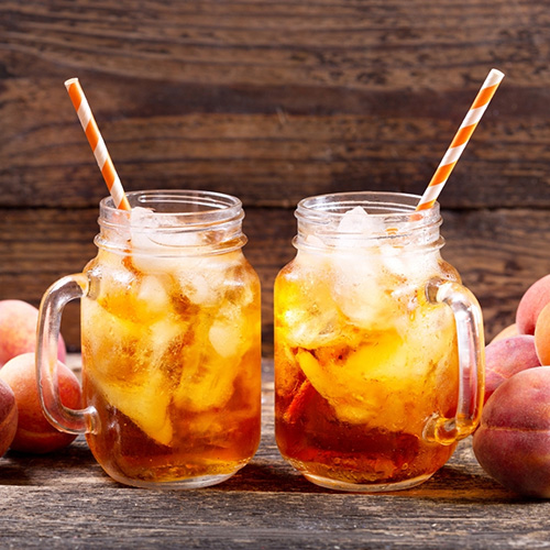 Two Phantom Peach Teas in mason jars with ice and a straw