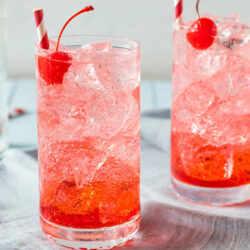 Two glasses of Raz the Phantom filled with ice and garnished with a cherry